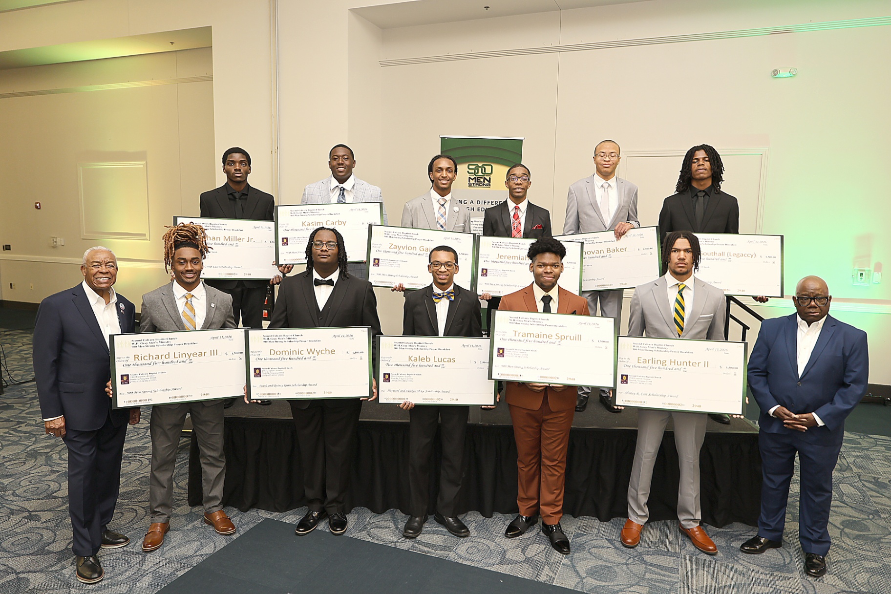 2026 scholarship recipients holding their awards at the 900 Men Strong breakfast